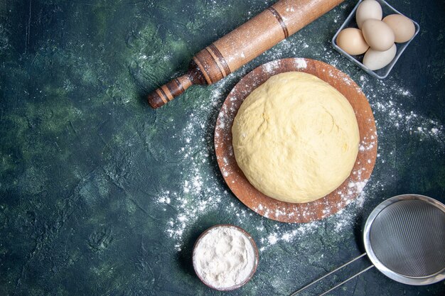 ダークブルーの背景に白い小麦粉と卵が入った上面図生生地ペストリーベイクケーキパイ生の新鮮なオーブン生地ホットケーキ