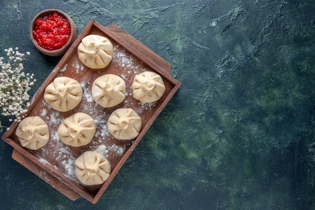 Вид сверху сырые пельмени с мясом внутри на темном фоне цветное тесто для еды блюдо из мясной муки приготовление перца