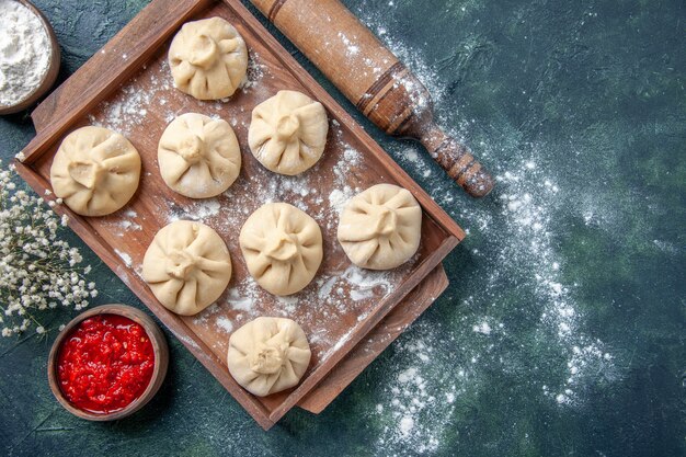 Top view raw dumplings with meat inside on the dark background meal cooking color flour pepper dish dough meat