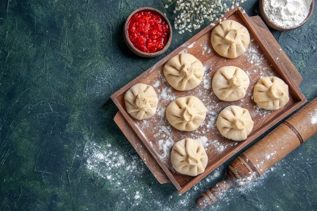 Top view raw dumplings with meat inside on dark background meal cooking flour pepper dish dough meat