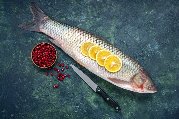 Top view raw fish pomegranates seeds in bowl knife on table