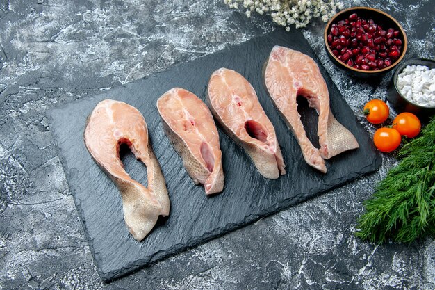 Top view raw fish slices on black board dill pomegranate seeds on table