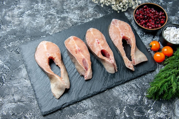 Top view raw fish slices on black board dill pomegranate seeds on table