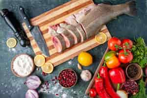 Foto gratuita vista dall'alto fette di pesce crudo coltello su tagliere verdure su tavola da portata in legno macinapepe sul tavolo da cucina