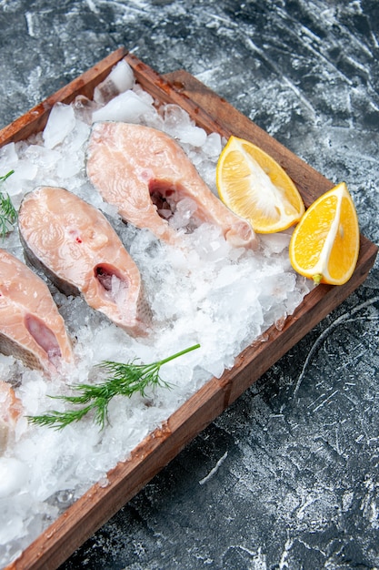 Fette di pesce crudo vista dall'alto con fette di limone ghiaccio su tavola di legno sul tavolo