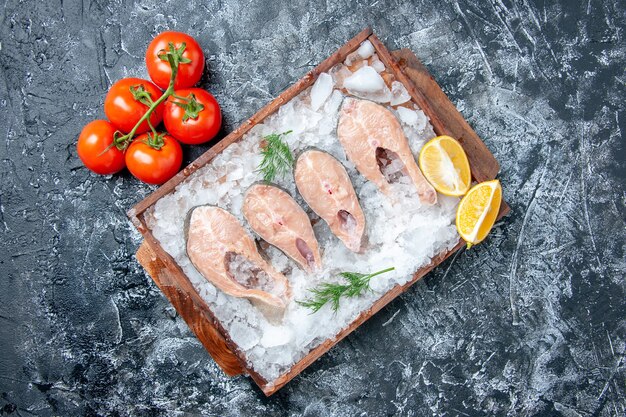 木の板の上の氷とテーブルの空きスペースに新鮮なトマトの上面図生の魚のスライス