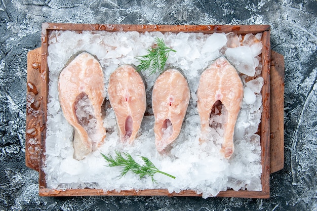 Top view raw fish slices with ice on wood board on table