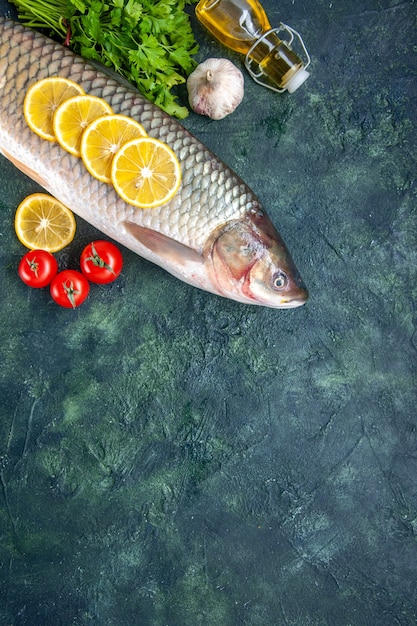 Top view raw fish tomatoes lemon slices oil bottle on table with free space