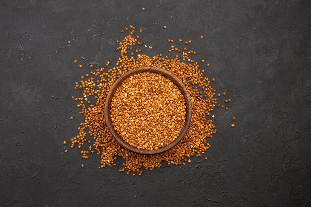 Top view raw fresh buckwheat inside plate on dark space