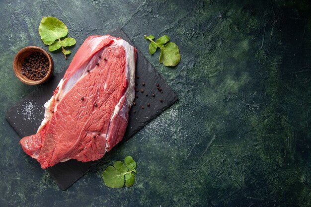 Вид сверху сырого свежего красного мяса на разделочной доске перец на зеленом черном фоне цветов смеси