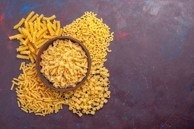 Top view raw italian pasta different formed on the dark purple background ingredient food meal raw