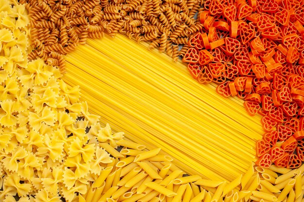 Top view raw italian pasta different shaped on light-grey background