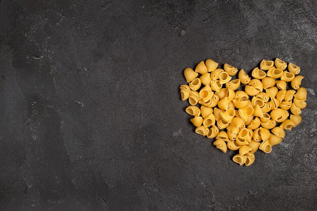 Top view of raw italian pasta heart shaped on the dark surface