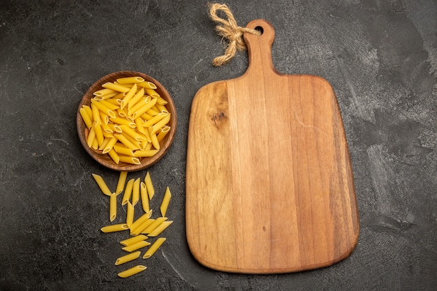 Pasta italiana cruda vista dall'alto all'interno del piatto marrone su grigio