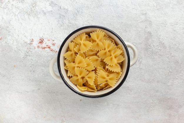 上面図白い背景の上の小さな鍋の中の生のイタリアンパスタ食品食事生の写真