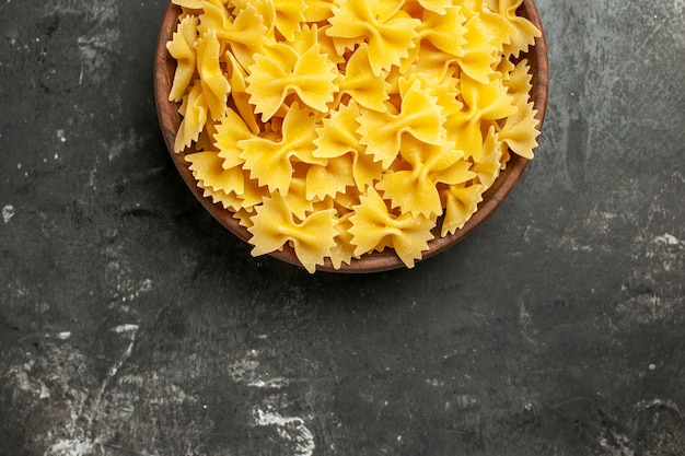 Free photo top view raw italian pasta inside plate on dark-grey background