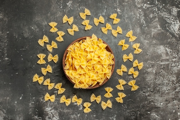 Top view raw italian pasta inside plate on dark-grey background