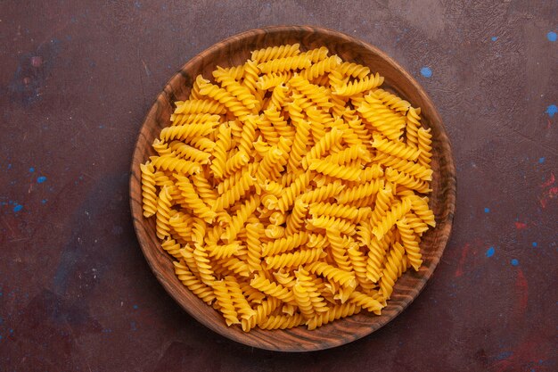 Top view raw italian pasta inside wooden tray on dark background product ingredient meal food vegetable