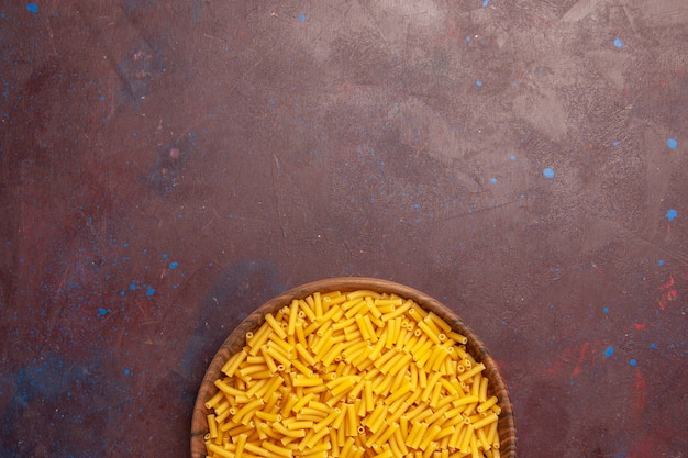 Free photo top view raw italian pasta little formed on dark-purple background vegetable pasta meal food color