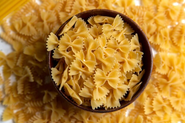 A top view raw italian pasta little formed with brown plate on the bright desk pasta italian food meal