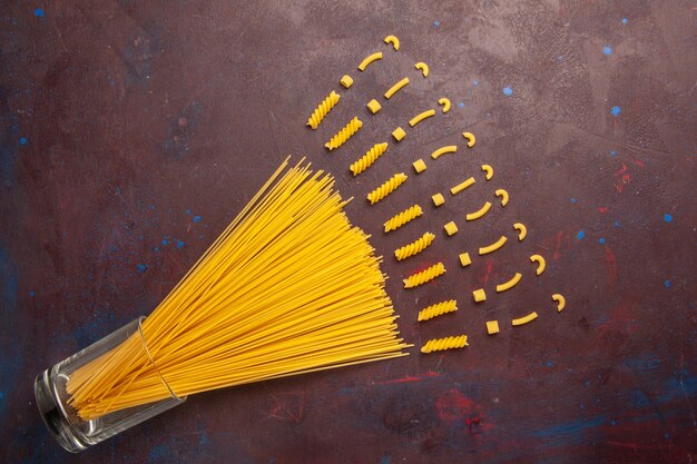 Top view raw italian pasta long formed yellow colored on the dark background pasta italy dough meal raw food color