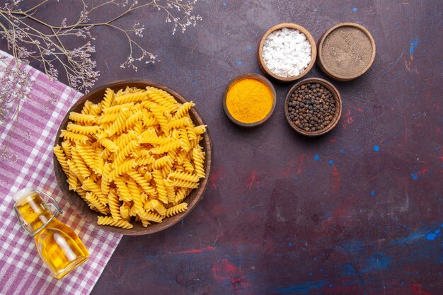 Top view raw italian pasta with different seasonings on a dark surface pasta food meal ingredients color