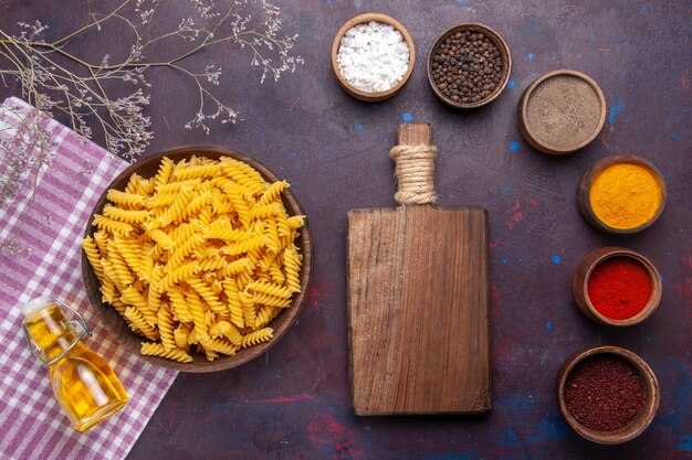 Top view raw italian pasta with different seasonings on dark surface pasta food meal ingredients color