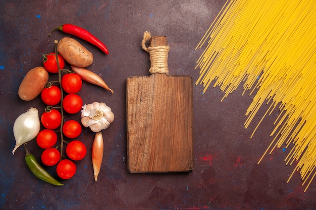 Free photo top view raw italian pasta with fresh vegetables on a dark background pasta italy dough meal food color