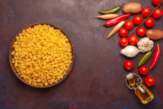 Top view raw italian pasta with fresh vegetables on dark background vegetable pasta meal food color