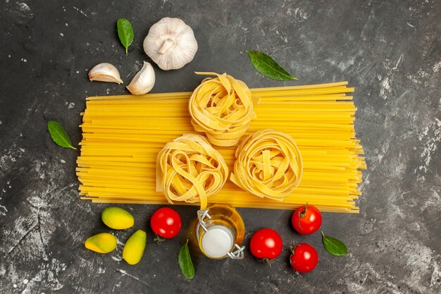 Top view raw italian pasta with garlic and tomatoes on a light-grey background