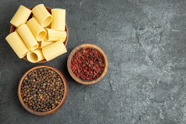 Top view raw italian pasta with seasonings on the grey background pasta dough meal raw spicy