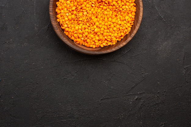 Top view raw lentil inside plate on the dark space