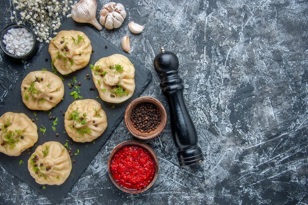 Top view raw little dumplings with garlic and tomato sauce on light gray background meat cuisine meal dinner cake dough cooking dish