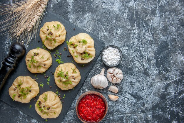 Top view raw little dumplings with garlic and tomato sauce on a light gray background meat cuisine meal dough cooking dish cake dinner