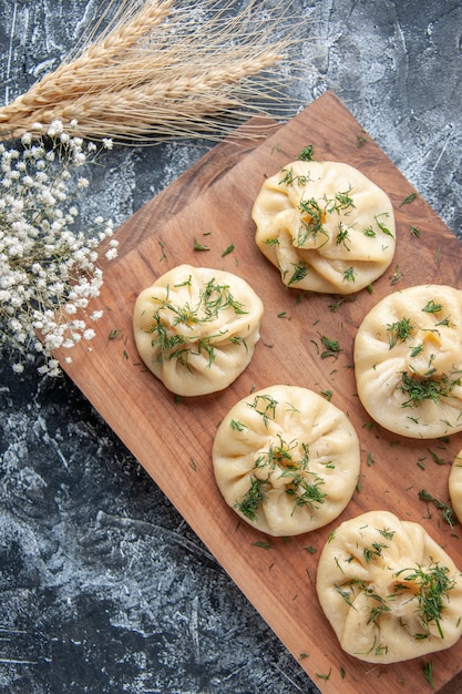 Бесплатное фото Вид сверху сырые маленькие пельмени с мясом и томатным соусом на серой поверхности тесто мука торт пирог кухня блюдо ужин мясо