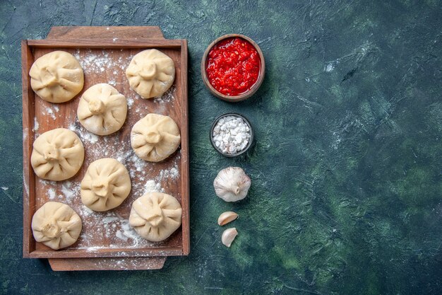 Top view raw little dumplings with meat inside on dark background meal color dish meat cooking flour dough