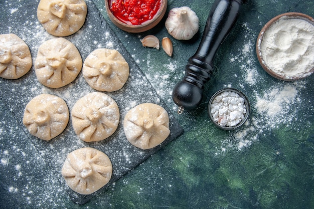 Top view raw little dumplings with meat inside on a dark background meat color dish cuisine dough flour cooking meal