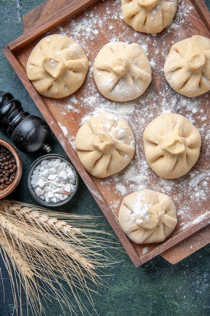 Top view raw little dumplings with meat inside on dark surface color meal dish flour dough meat