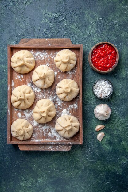 Top view raw little dumplings with meat inside on a dark surface meal color dish meat cooking flour dough