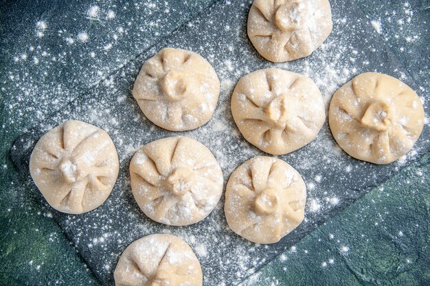 Top view raw little dumplings with meat inside on a dark surface meat color dish raw meal cuisine dough flour cooking