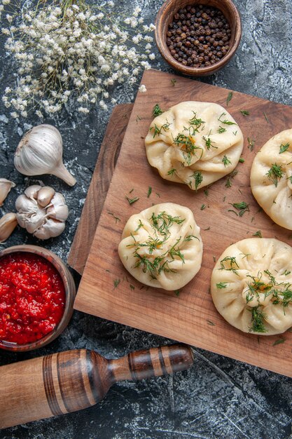 Top view raw little dumplings with meat and tomato sauce on the gray surface dough hotcake cooking cuisine meal cake pie