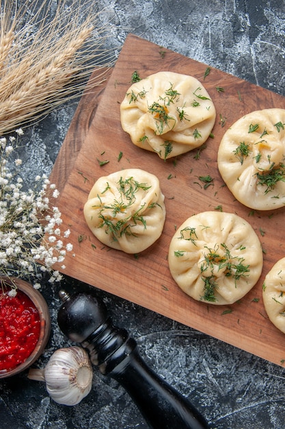 Top view raw little dumplings with meat and tomato sauce on a gray surface dough meal cake pie dish dinner cuisine meat cooking