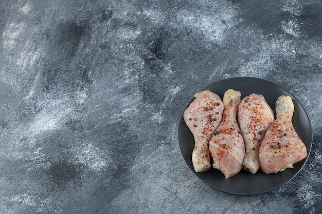 Top view of raw marinated chicken legs on grey background.