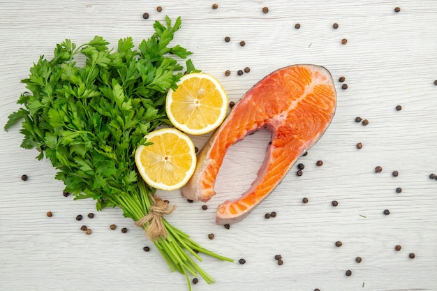 Top view raw meat slice with greens and lemon on white background