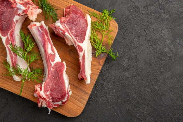 Top view raw meat slices with greens on dark background cow color meat photo animal pepper chicken raw free space