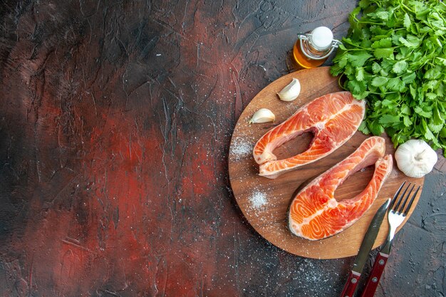 Top view raw meat slices with greens on a dark background