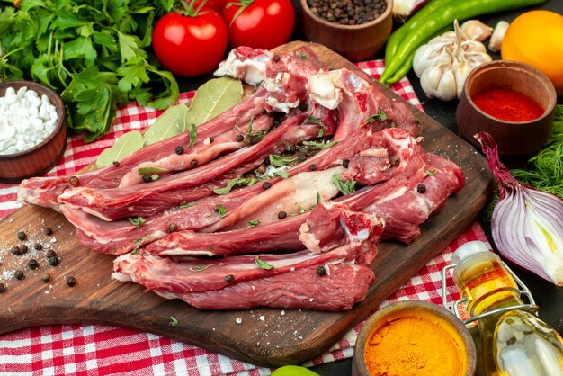 Top view raw meat slices with greens and fresh vegetables on dark background meal meat butcher salad food cooking