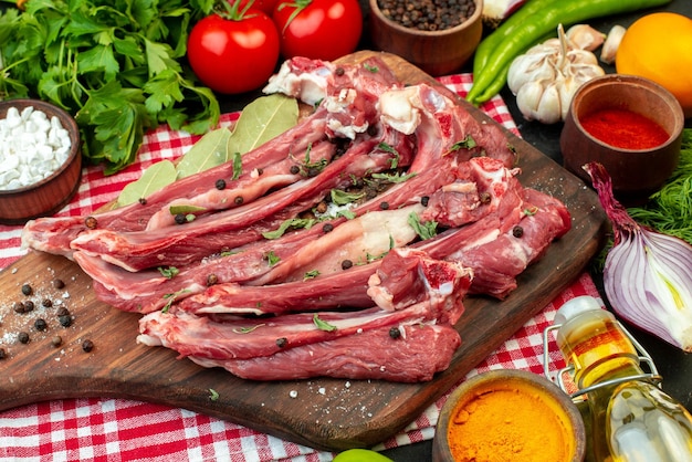 Top view raw meat slices with greens and fresh vegetables on dark background meal meat butcher salad food cooking