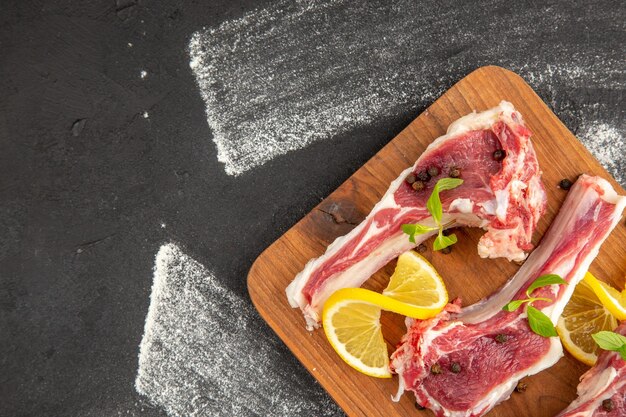 Top view raw meat slices with greens and lemon on dark background meat chicken salad vegetable cow color photo animals