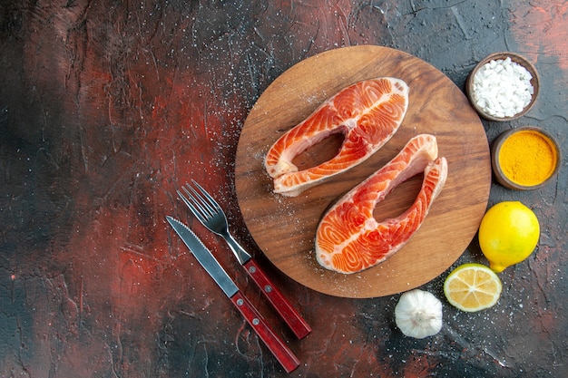 Foto gratuita fette di carne cruda vista dall'alto con condimenti e limone su sfondo scuro